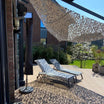 Grijs driehoekig camouflagenet boven een terras met ligstoelen