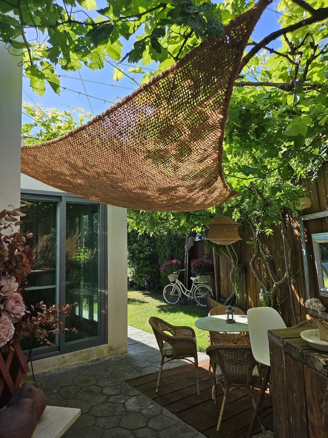 Driehoekig kokos zonnezeil in een tuin met veel groen