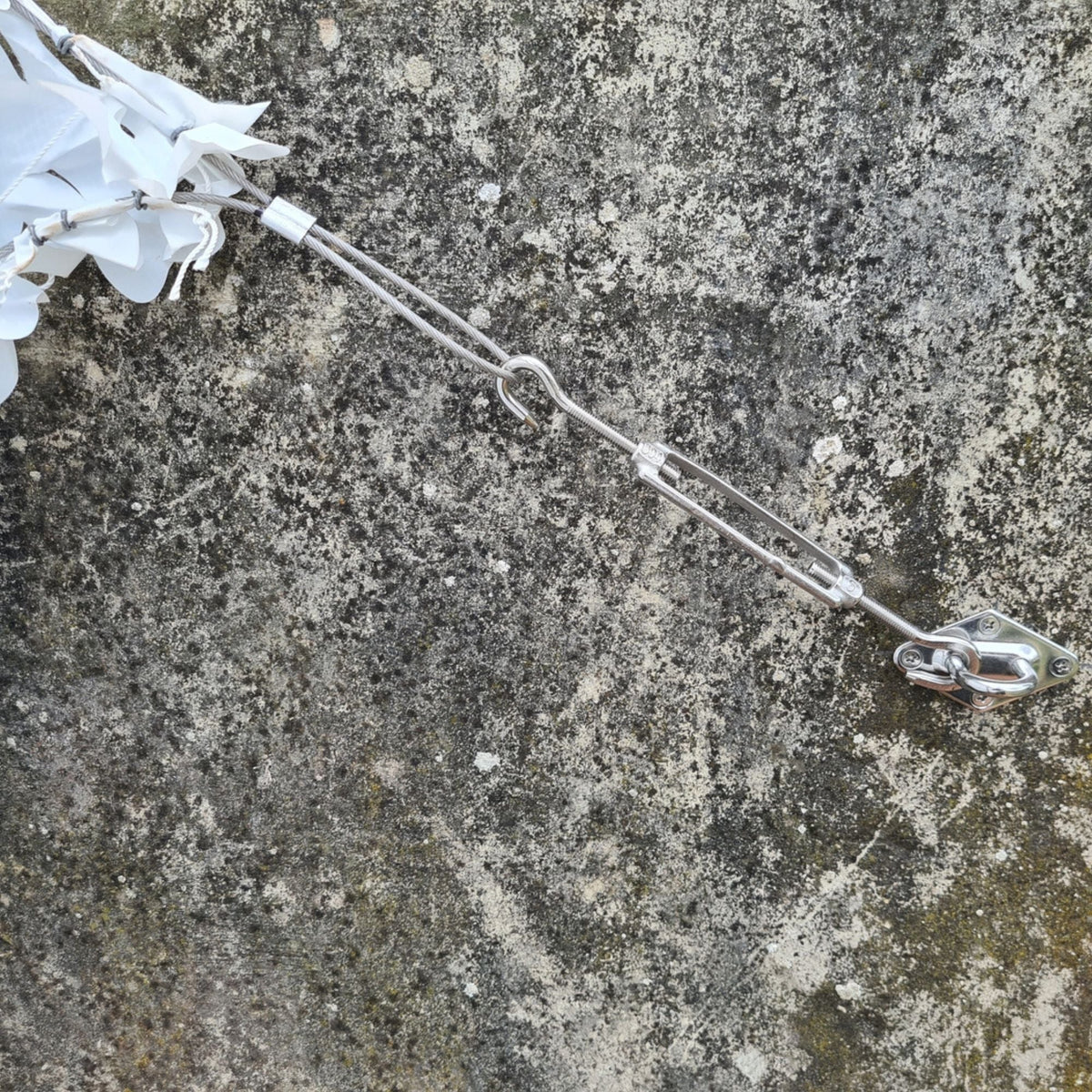Spanner en bevestigingshaak aan een stenen muur met hoek van wit camouflagenet